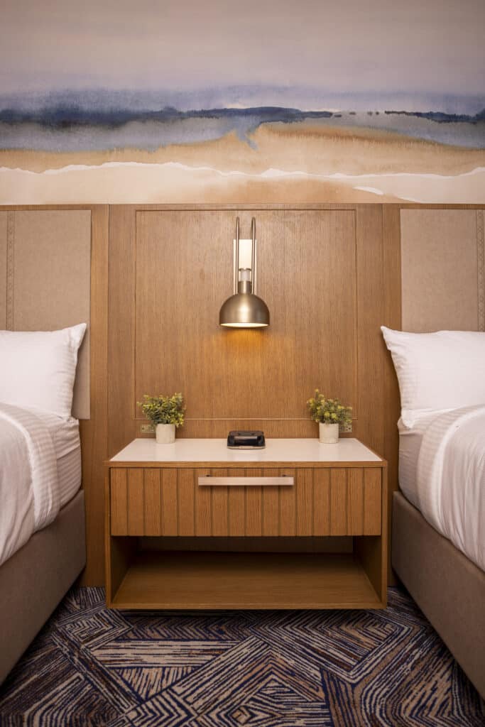 Double Queen bedside table with warm pendant lighting, easy charging and soft wood accents at Golden Mesa Hotel.