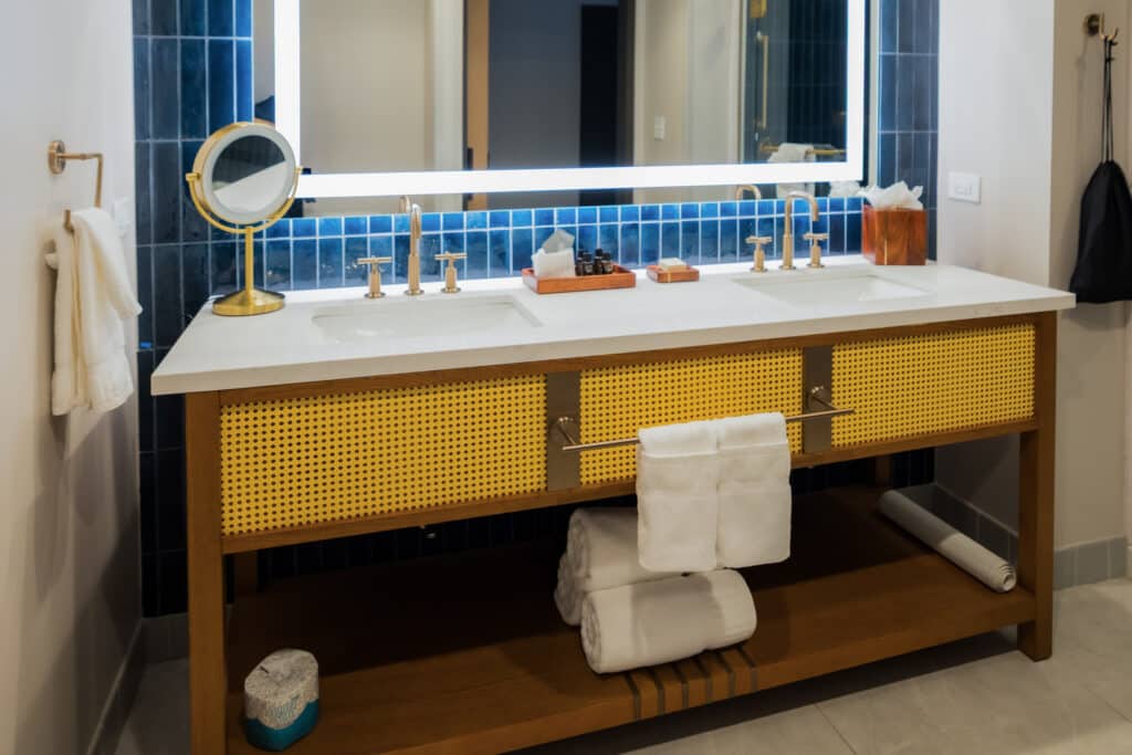 Double Queen bathroom with double-sink vanity, illuminated mirror, soft towels and blue tile at Golden Mesa Hotel.