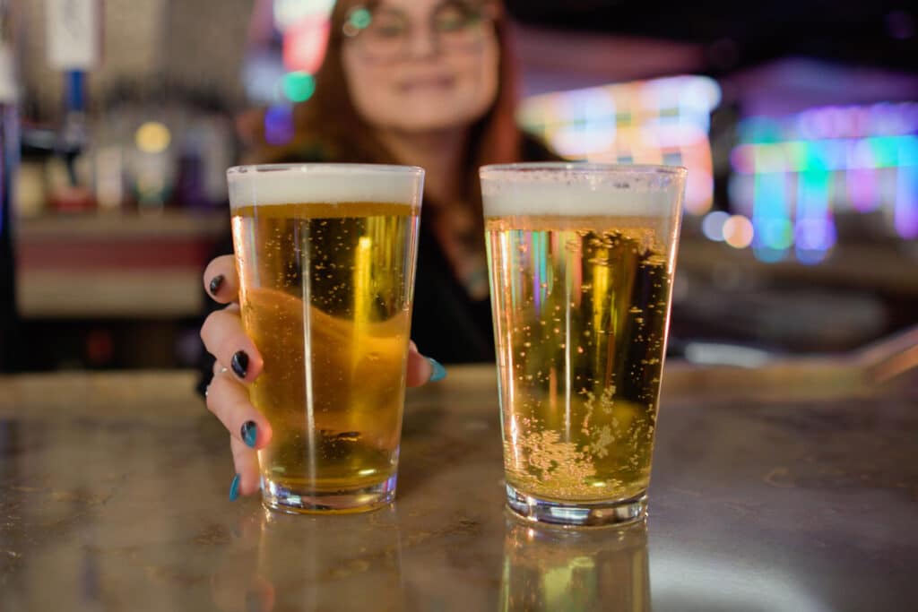 Two pints of beer on the bar at Gold Spur Bar inside Golden Mesa Casino & Hotel, with colorful casino lights in the background.