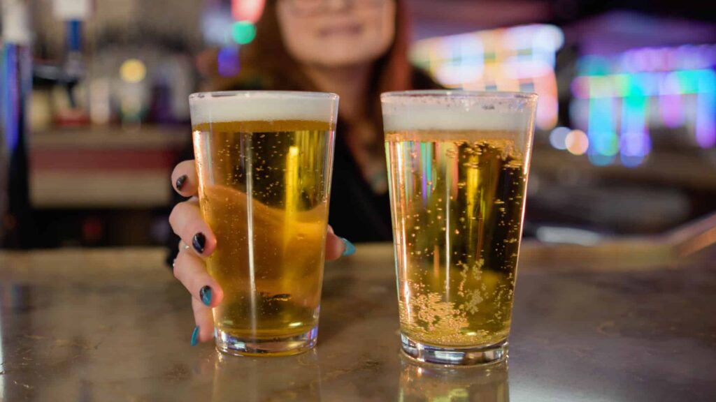Two pints of beer on the bar at Gold Spur Bar inside Golden Mesa Casino & Hotel, with colorful casino lights in the background.