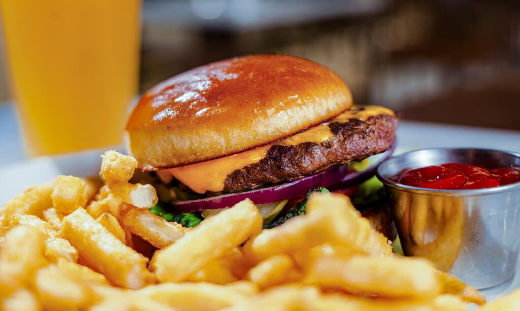 Close-up of a cheeseburger with fries, ketchup and beer served at Golden Mesa's Cimarron Ridge Restaurant.