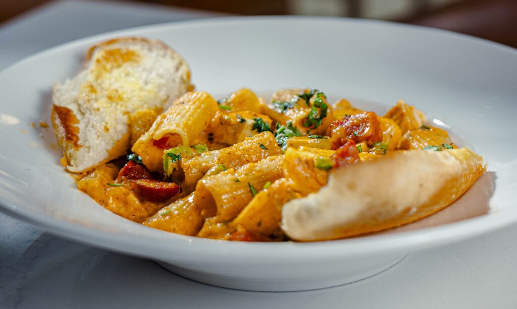 Creamy Cajun chicken pasta with toasted bread served in a white bowl, served at Golden Mesa's Cimarron Ridge Restaurant.