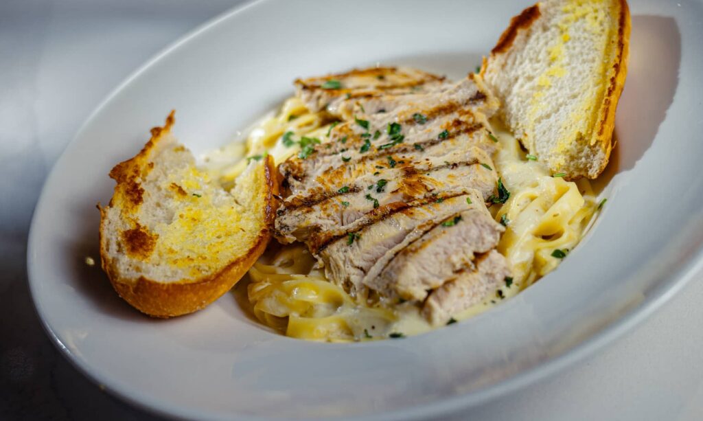 Chicken fettuccine alfredo topped with grilled chicken and served with garlic bread at Golden Mesa's Cimarron Ridge Restaurant.