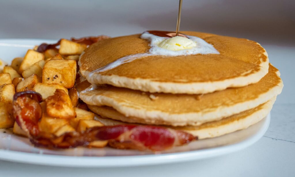 Stack of pancakes with butter, syrup, bacon and breakfast potatoes served at Golden Mesa's Cimarron Ridge Restaurant.