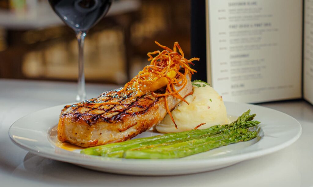 Grilled pork chop with mashed potatoes, asparagus and red wine served at Golden Mesa's Cimarron Ridge Restaurant.