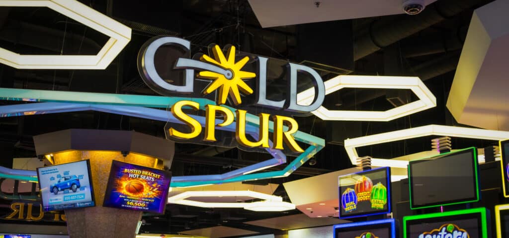 Gold Spur Bar sign above the central bar on the Golden Mesa casino floor, surrounded by glowing lights and slot machines.