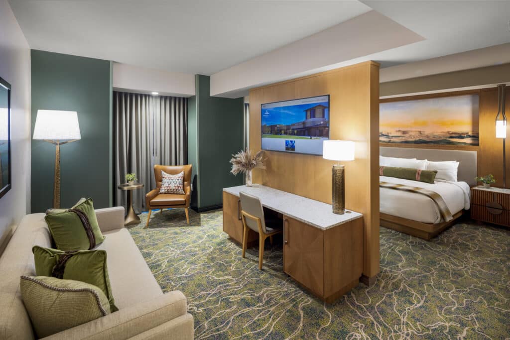 Junior King Suite with divided living area, plush lounge seating, work desk, warm lighting and king bed at Golden Mesa Hotel.