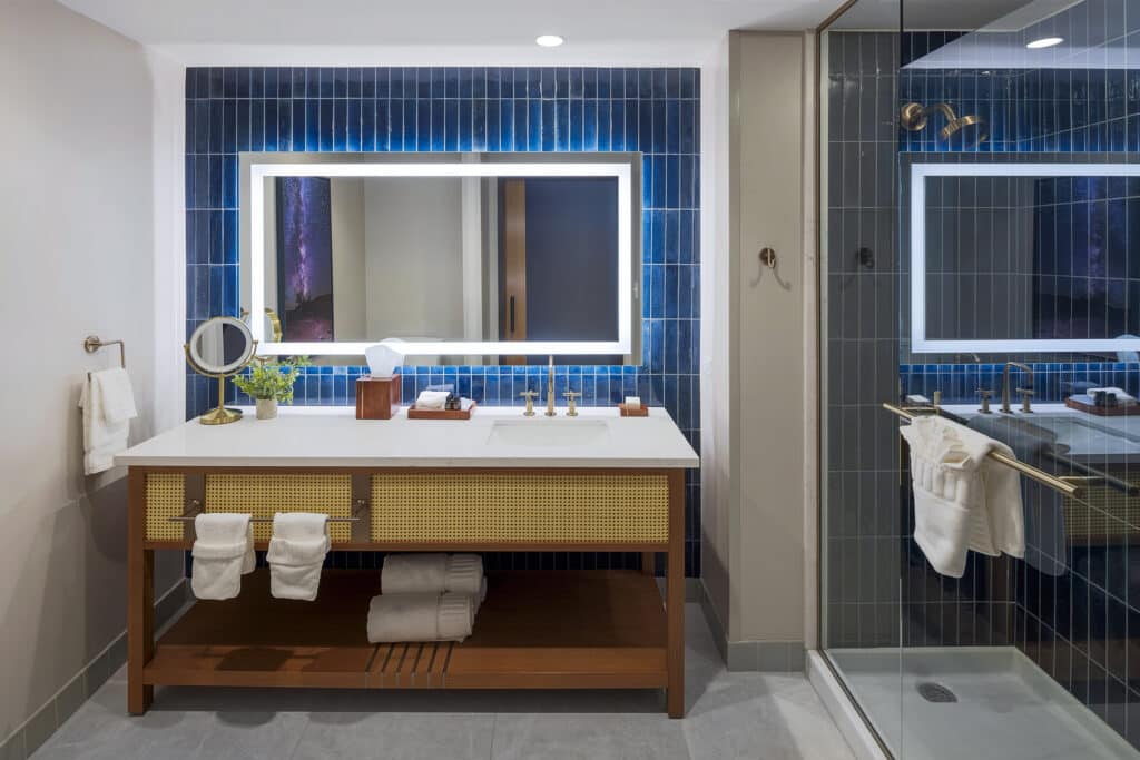 King Deluxe bathroom with glass shower, deep blue tile, illuminated mirror and wide vanity at Golden Mesa Hotel.