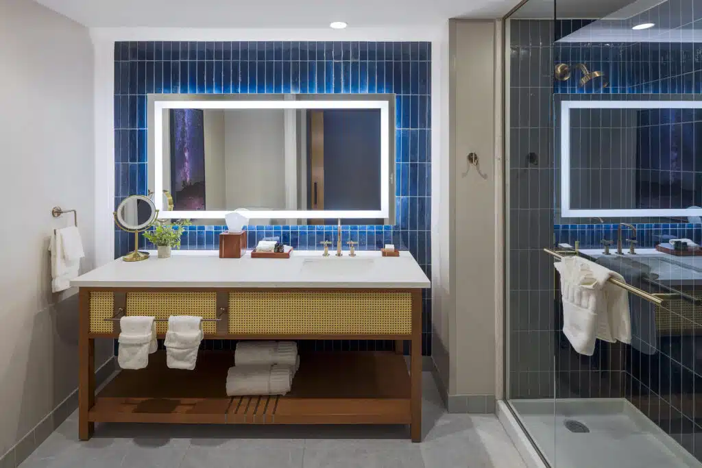 King Deluxe bathroom with glass shower, deep blue tile, illuminated mirror and wide vanity at Golden Mesa Hotel.