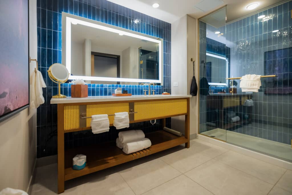King Deluxe bathroom with glass shower, deep blue tile, illuminated mirror and wide vanity at Golden Mesa Hotel.