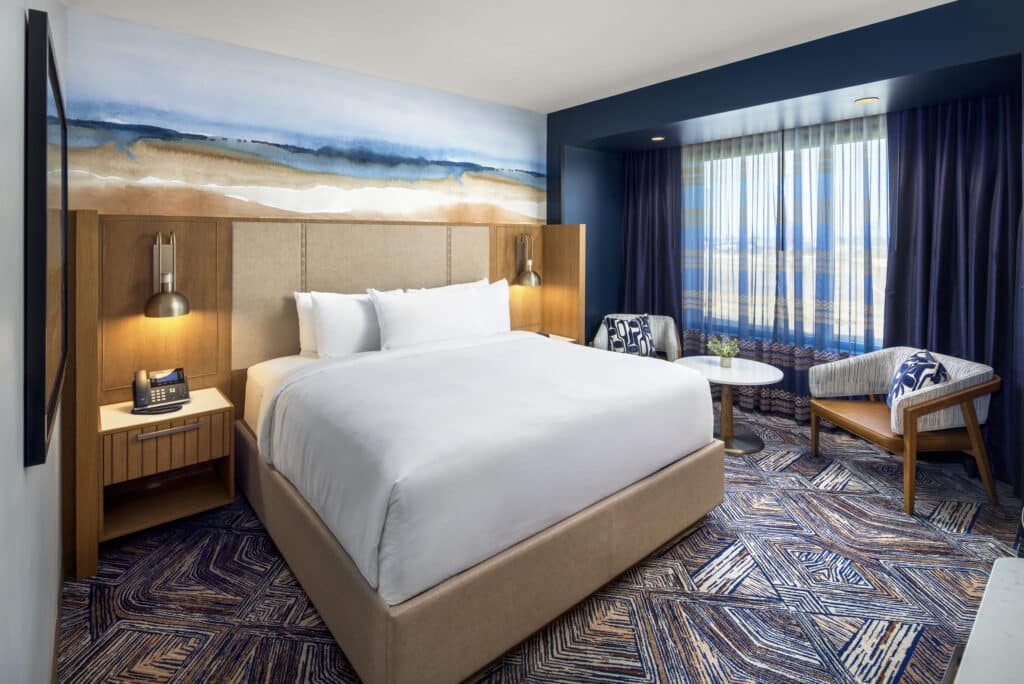 King bed with pristine white bedding, soft bedside lighting, and a two-chair seating area in a Golden Mesa Hotel Standard King room.