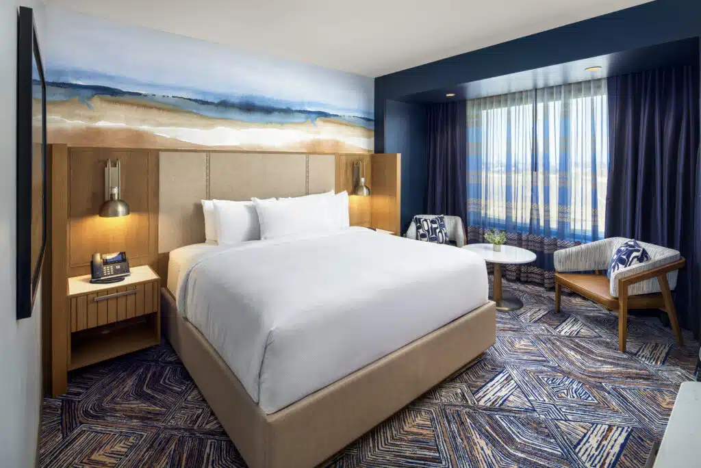 King bed with pristine white bedding, soft bedside lighting, and a two-chair seating area in a Golden Mesa Hotel Standard King room.