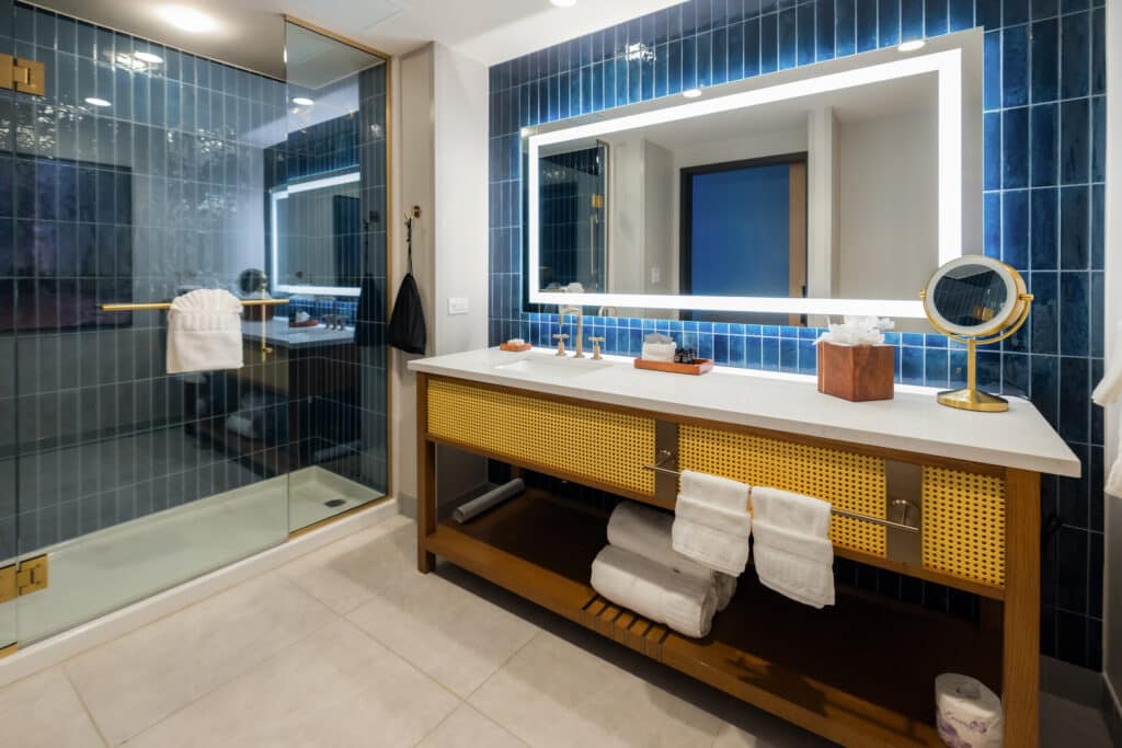 King Standard bathroom with glass shower, deep blue tile, illuminated mirror and wide vanity at Golden Mesa Hotel.