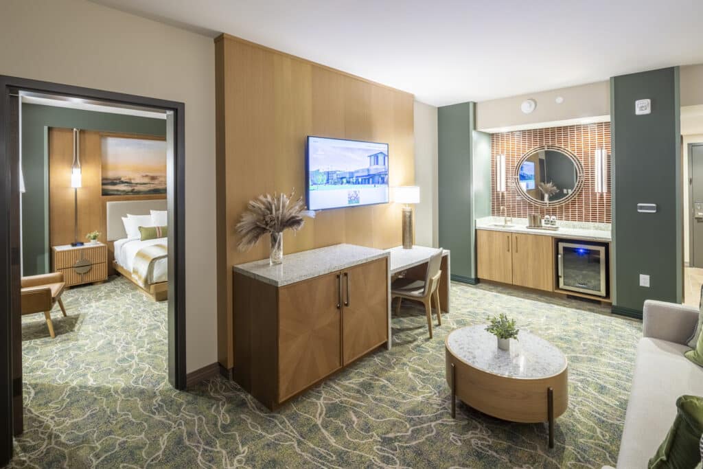 Spacious King Suite living room with TV, desk, coffee table, couch and bedroom visible through the doorway at Golden Mesa Hotel.