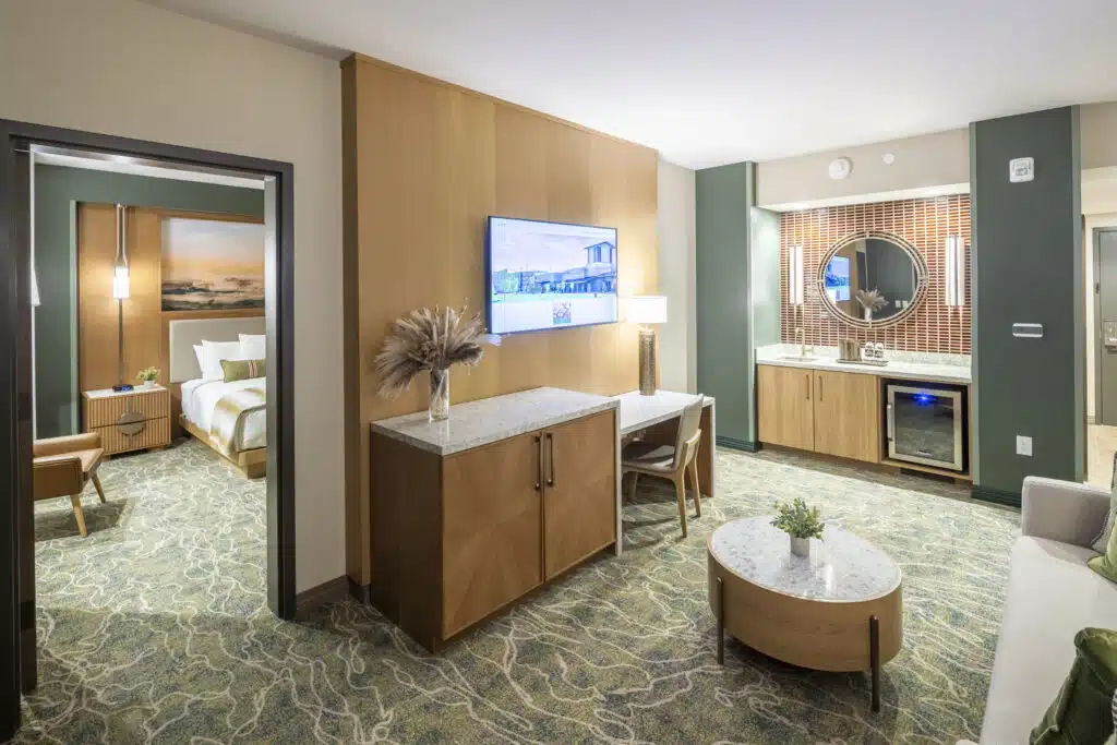 Spacious King Suite living room with TV, desk, coffee table, couch and bedroom visible through the doorway at Golden Mesa Hotel.