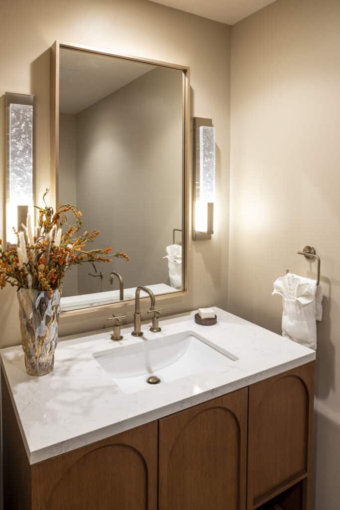 Additional half-bathroom with marble vanity, warm wall lighting and floral decor in a Golden Mesa Hotel King Suite.