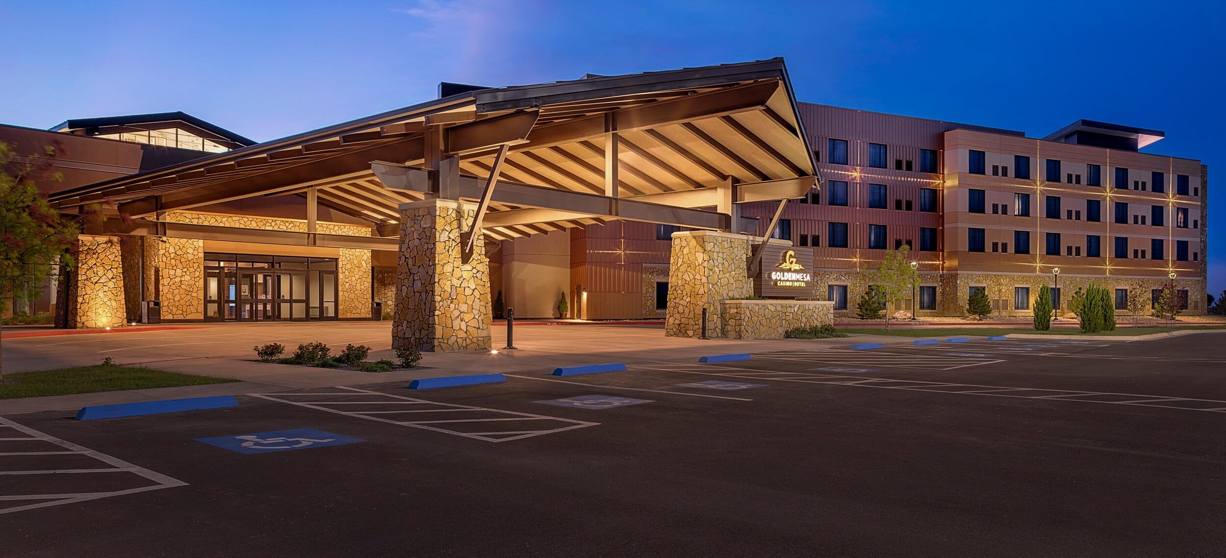 Golden Mesa Casino & Hotel exterior at dusk with covered entrance, stone columns, hotel tower and accessible parking.