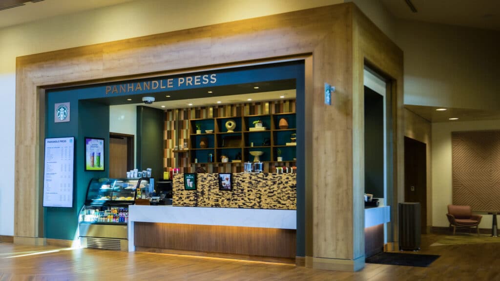 Panhandle Press Coffee Shop with wood framing, menu screens, pastry case and Starbucks coffee inside Golden Mesa Hotel lobby.