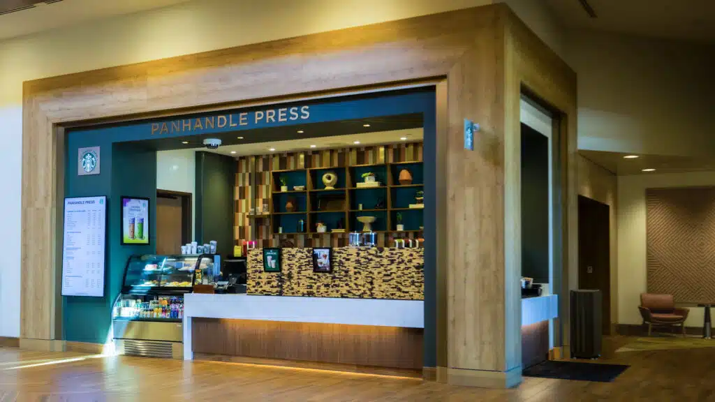Panhandle Press Coffee Shop with wood framing, menu screens, pastry case and Starbucks coffee inside Golden Mesa Hotel lobby.