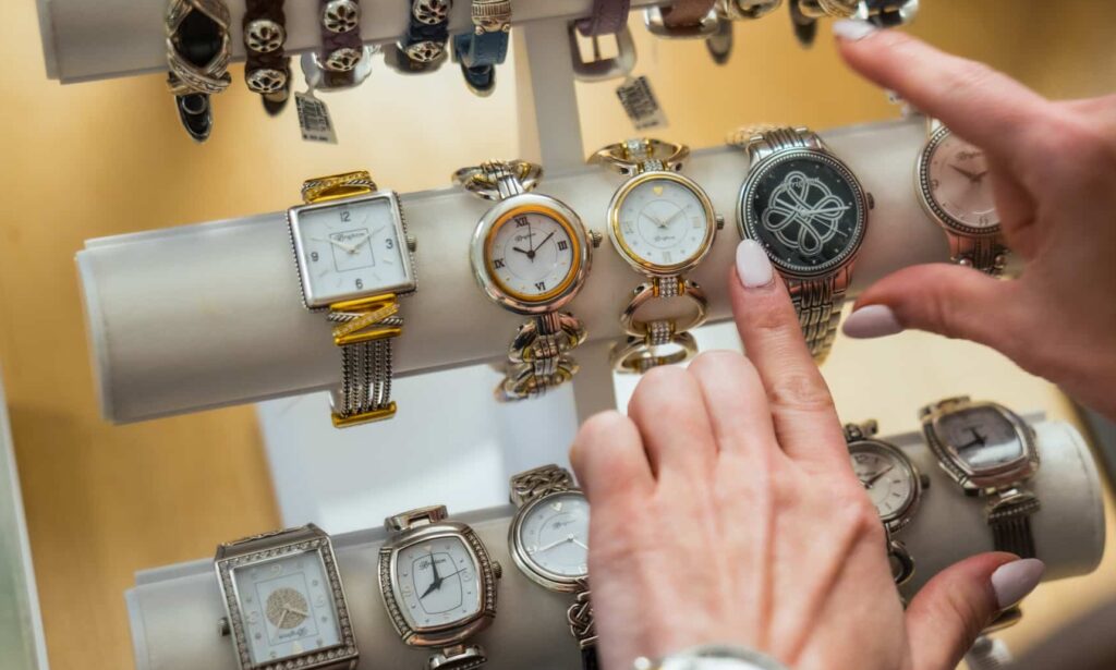Close-up of a guest’s hands browsing watches at Silver Saddle Gift Shop inside Golden Mesa Casino & Hotel.