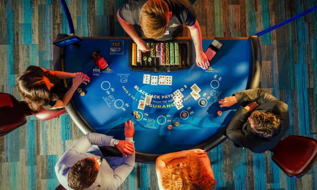 Overhead view of guests playing blackjack at a Golden Mesa Casino table with chips, cards and dealer on the casino floor.