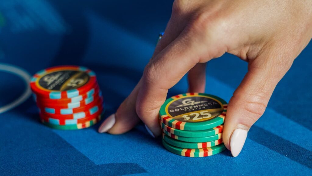 Close-up of a guest stacking $25 chips on a Golden Mesa Casino table game.