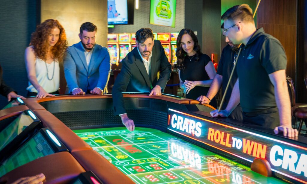 Guests gather around the electronic craps table on the Golden Mesa Casino floor for a lively group gaming experience.