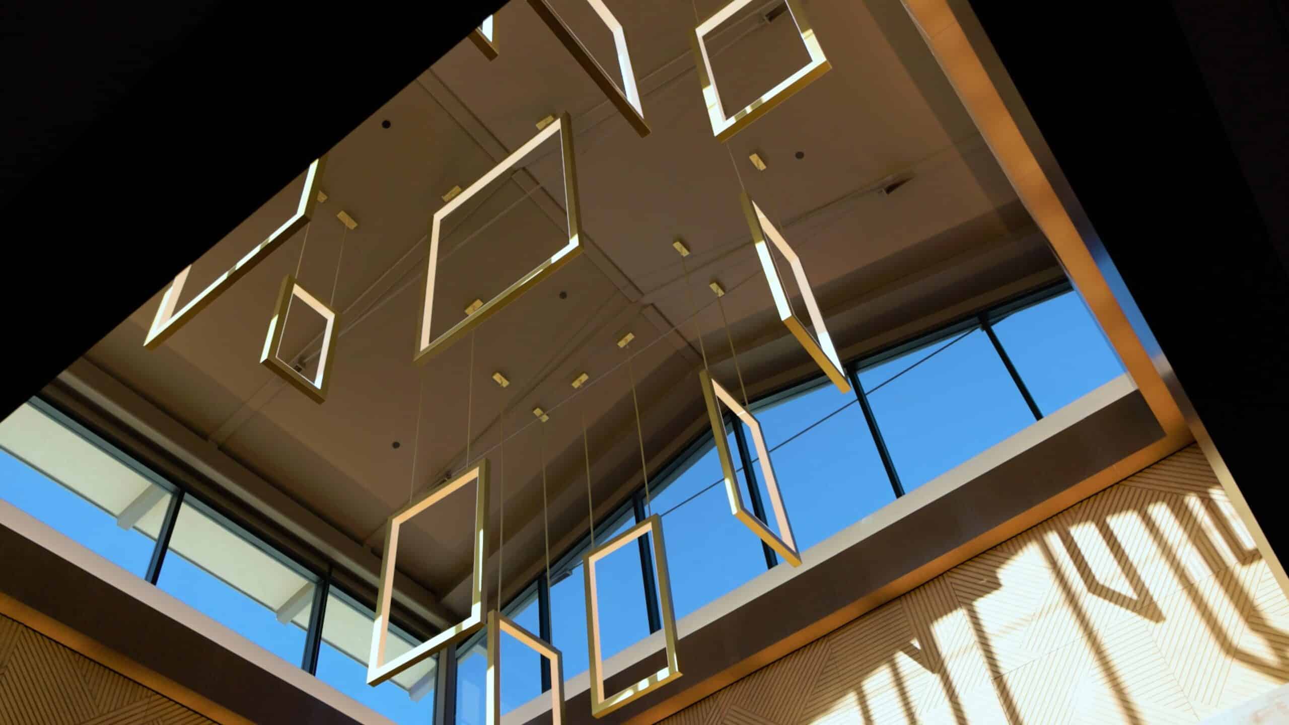 Hotel lobby skylight with hanging geometric light installation and warm patterned walls at Golden Mesa Casino & Hotel.