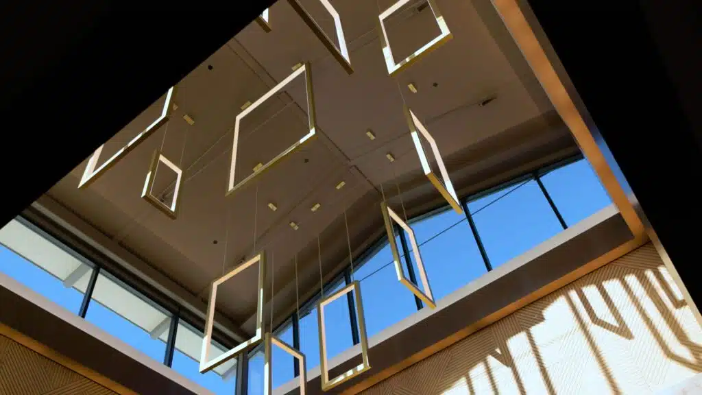 Hotel lobby skylight with hanging geometric light installation and warm patterned walls at Golden Mesa Casino & Hotel.