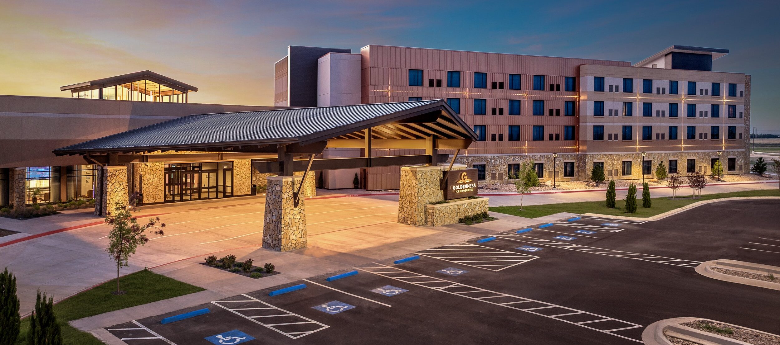 Golden Mesa Casino & Hotel exterior at dusk with hotel tower, covered entrance, stonework and parking in Guymon, Oklahoma.