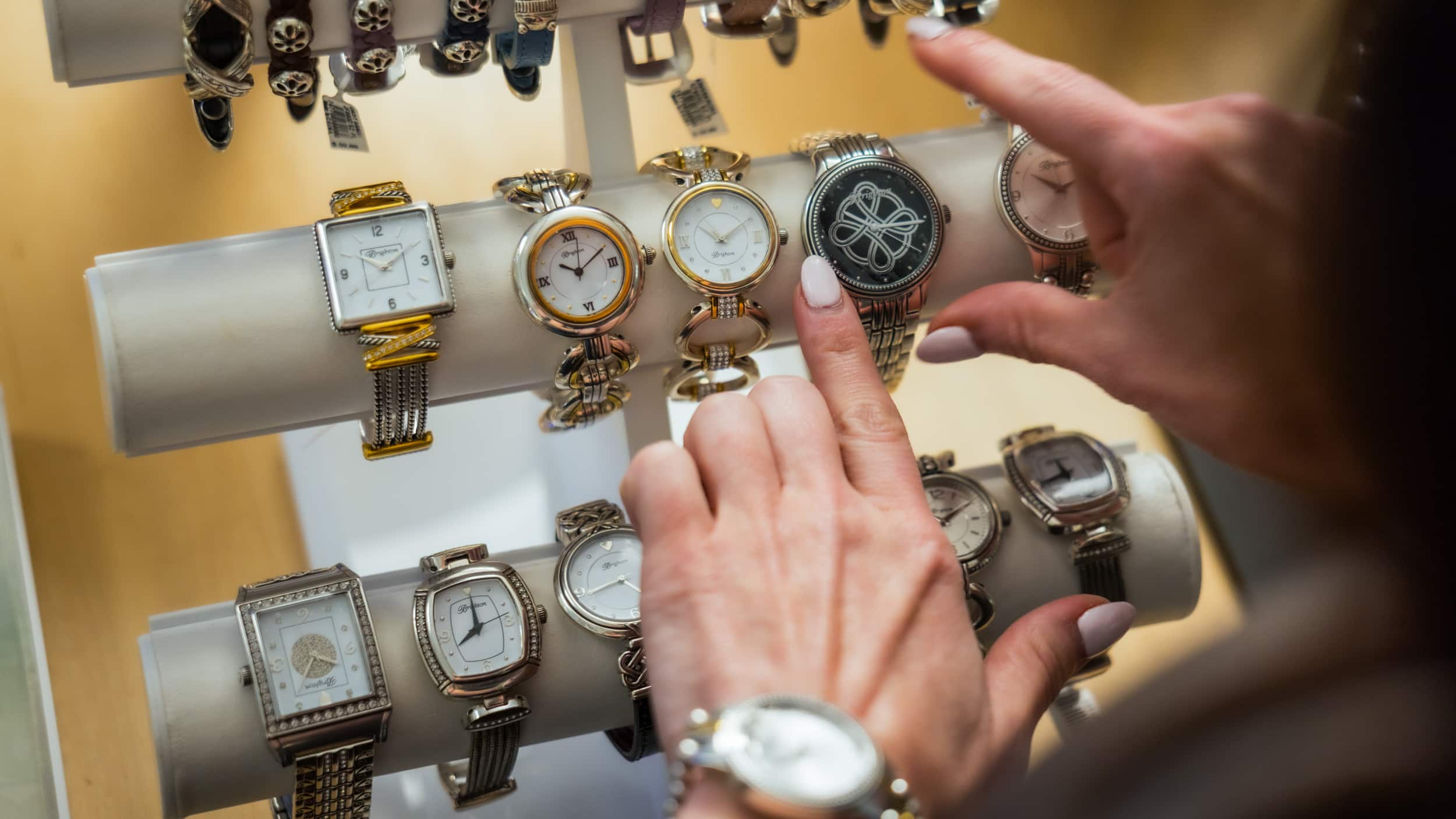 Close-up of a guest’s hands browsing watches at Silver Saddle Gift Shop inside Golden Mesa Casino & Hotel.