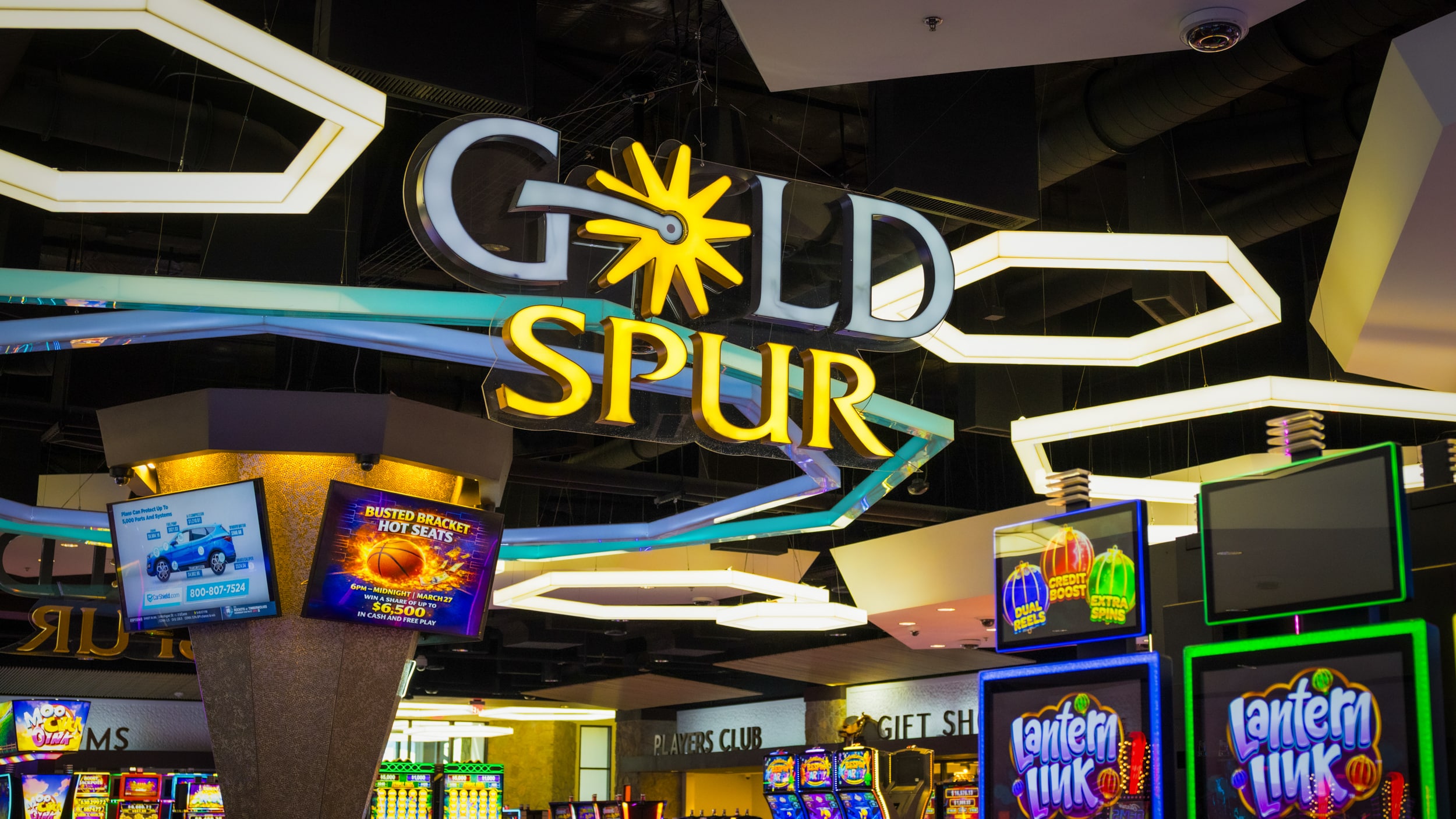 Gold Spur Bar sign above the central bar on the Golden Mesa casino floor, surrounded by glowing lights and slot machines.